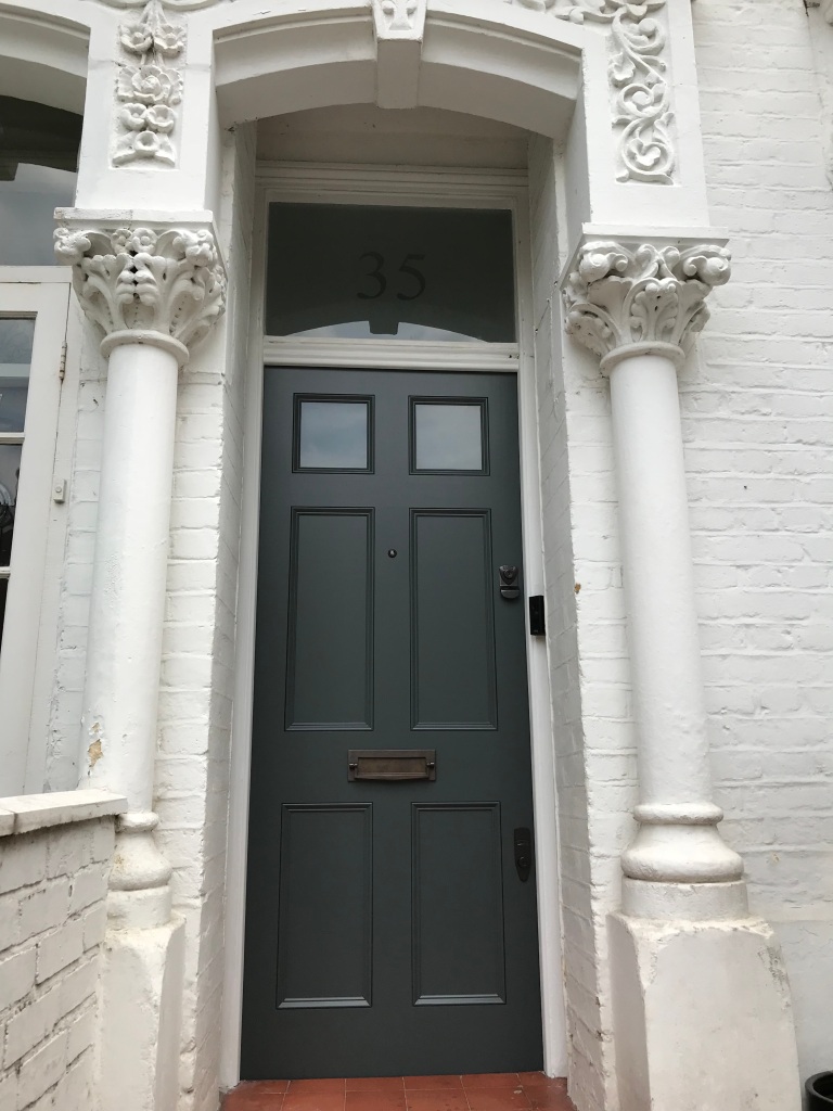 Victorian door with half solid panelling, top-glazed panelling and bronze door furniture.