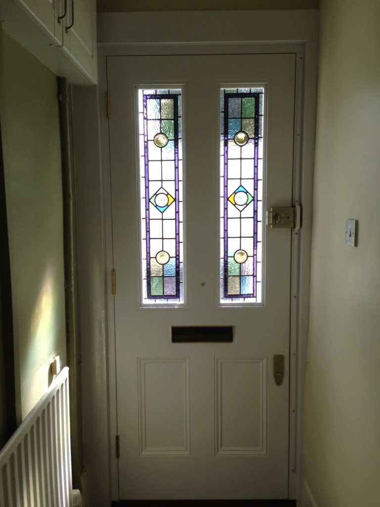 A Victorian front door design with half glazed panelling and gleaming chrome door furniture.